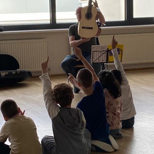 Ein Lehrer hält die Gitarre hoch