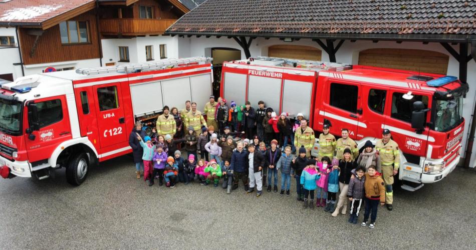 Gruppenfoto mit den Kindern und den Feuerwehrleuten, vor den Feuerwehrautos