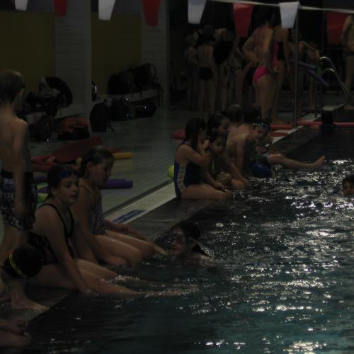 Kinder sitzen am Beckenrand und strampeln im Wasser
