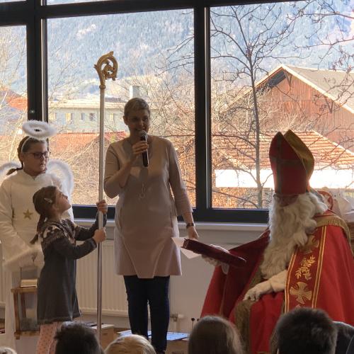Fr. Direktor spricht in ein Mikrophon neben Nikolaus und Engel