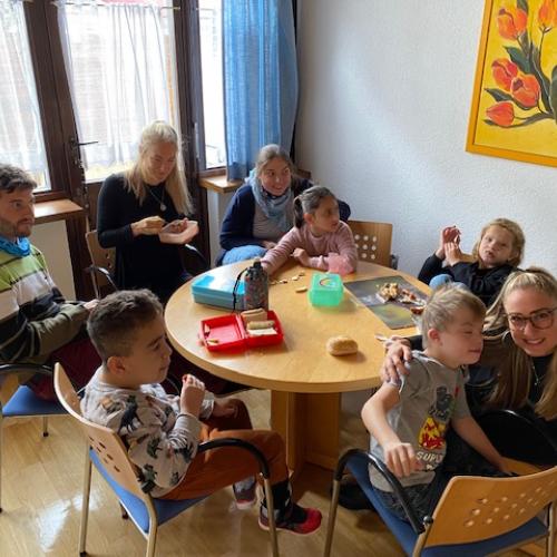 alle Kinder und Betreuer sitzen um einen Tisch beim Jausnen