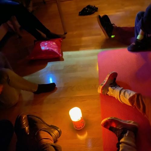 Kerze am Boden, die Füße der Kinder ringsherum