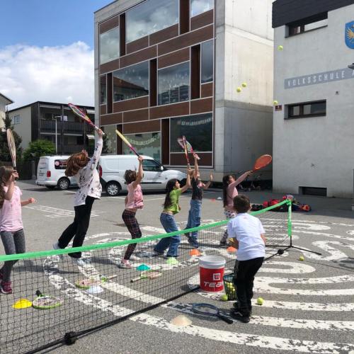 Kinder spielen den Tennisball über das Netz