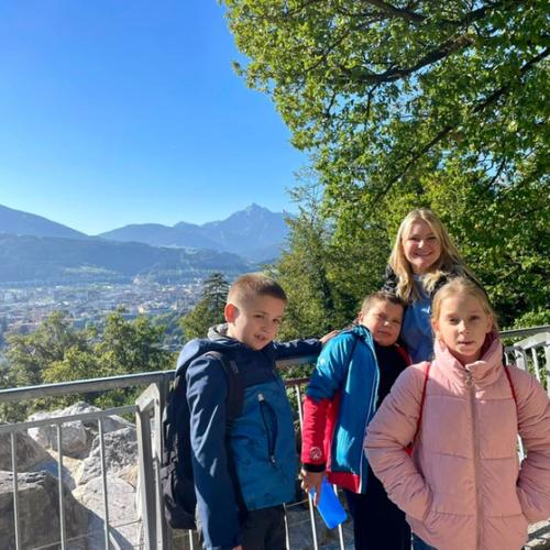 3 Kinder + Lehrerin stehen vor dem Panorama von IBK