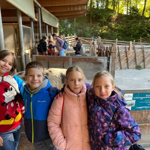 4 Kinder lachen in die Kamera - im Hintergrund der Stall