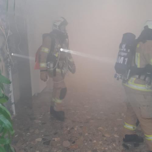 Feuerwehrmann im dichten Rauch mit Taschenlampe