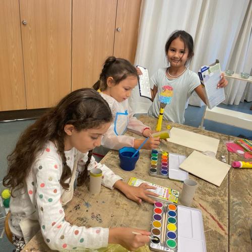 Kinder malen Holzstücke mit Wasserfarben an