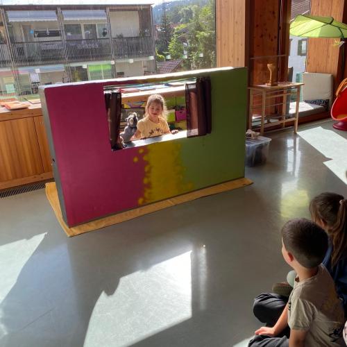 Kind mit Trisomie 21 spielt mit einer Handpuppe vor den Kindern