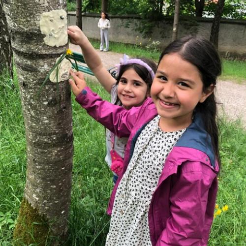 Kinder stehen am Baum und arbeiten an einem Baumgeist-Gesicht