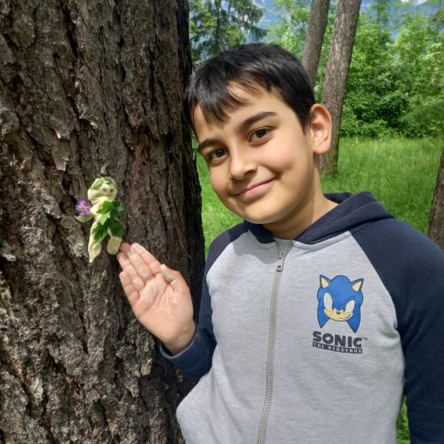 Junge neben einem Baum - er zeigt stolz auf sein Werk