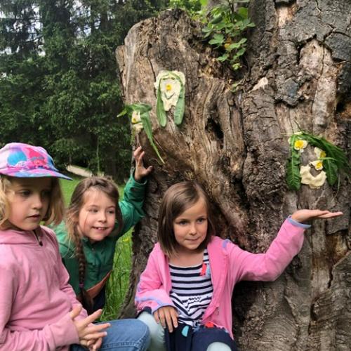3 Kinder stehen vor einem Baum und zeigen stolz ihre Werke