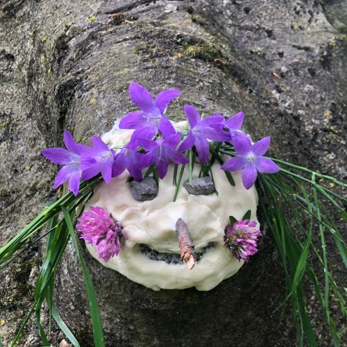 Baumgeist-Gesicht mit lila Blüten