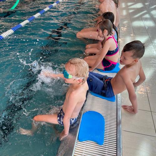 Kinder sitzen am Beckenrand