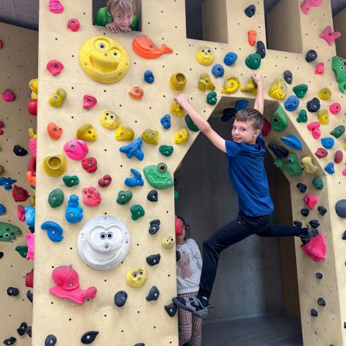 Kind klettert über einen Bogen in der Boulderhalle