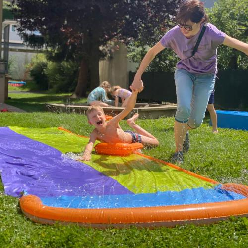 ein Kind wird über eine Wasserplane gezogen