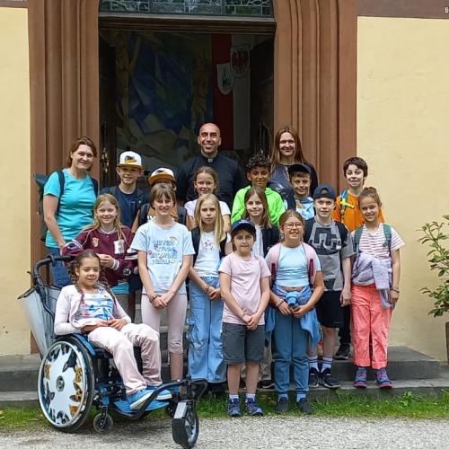 Klasse mit Rollstuhlkind steht am Kapelleneingang