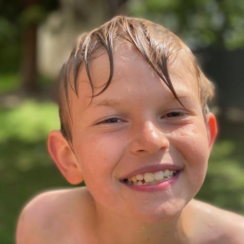 Bub mit nassen Haaren strahlt in die Kamera