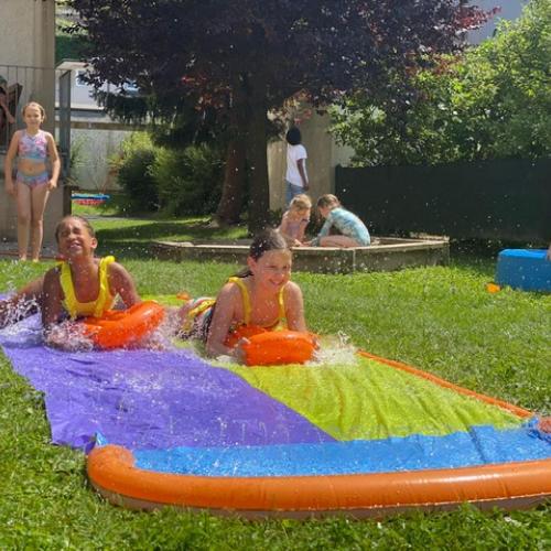 Kinder rutschen über eine Wasserplane