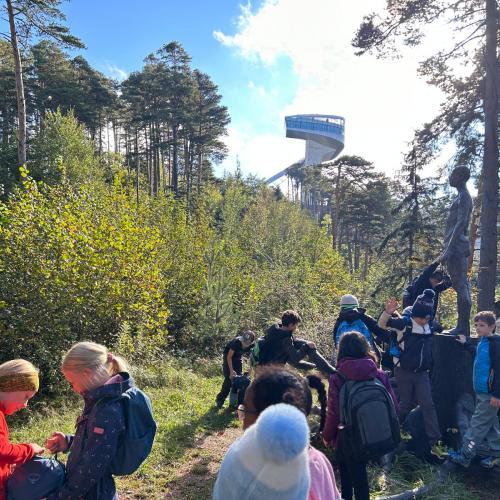 Kinder sitzen am Wanderweg und spielen im Hintergrund die Bergiselschanze 