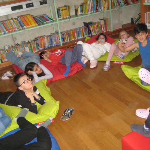 Die Kinder liegen auf Pölstern in der Bibliothek
