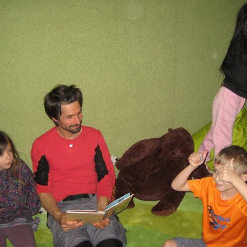 Die Kinder sitzen mit dem SCHUSO am Boden und haben Spaß