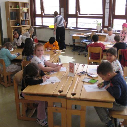 Kinder sitzen an den Tischen und Malen