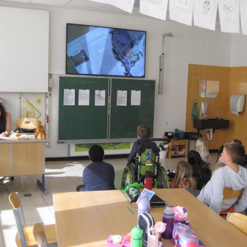 Während die Lehrerin liest, sehen die Kinder am Bildschirm die Bilder zum Buch