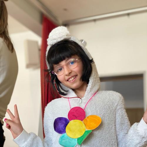 Ein Mädchen als Einhorn verkleidet mit bunter Blume um den Hals