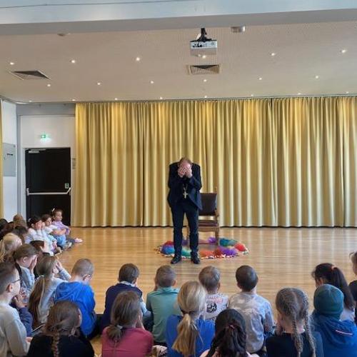 Der Bischof hält die Hände vor das Gesicht - im Vordergrund die Kinder