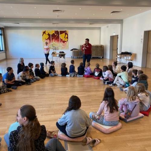 Kinder sitzen am Boden im Kreis