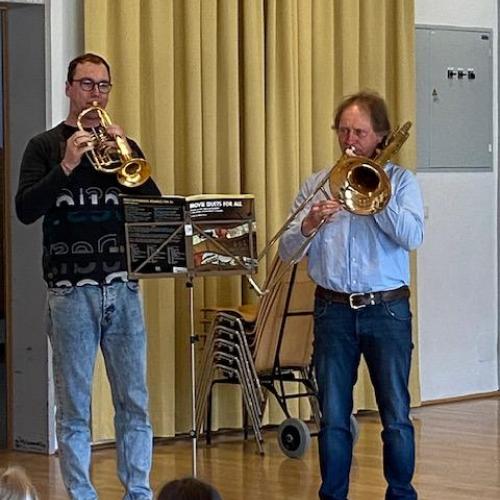 2 Lehrer spielen Trompete und Posaune
