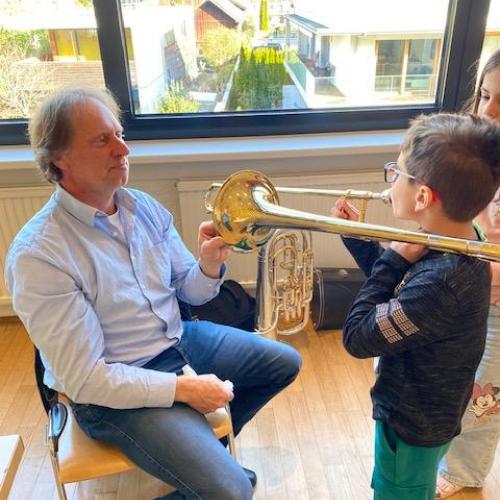 Kind spielt Posaune - Lehrer sitzt gegenüber