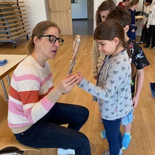 Lehrerin zeigt einem Mädchen die Querflöte