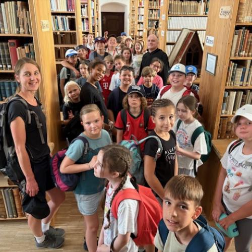 Eine Gruppe von KIndern lacht in der Bibliothek in die Kamera