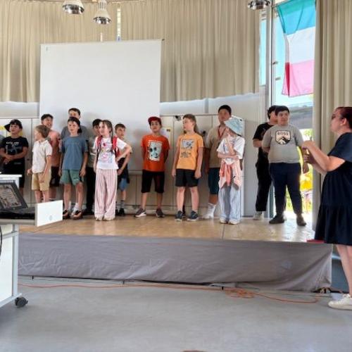 Unsere 4b singt auf der Bühne, Fr. Sigitz gibt den Einsatz