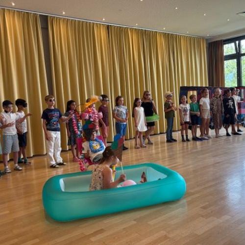 Kinder mit bunten Accesoires und einen aufblasbaren Becken im Vordergrund
