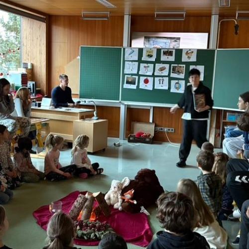 Die Kinder sitzen gebannt am Boden und hören der L zu