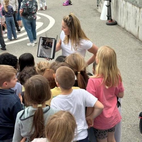 Lea Haslwanter zeigt den Kindern ein Video der Olympiafahrt im Eiskanal auf dem Tablet