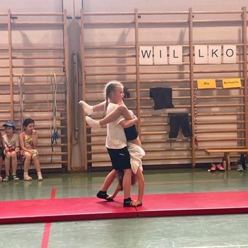 Ein Kind geht mit einem Handstand auf den Füßen eines anderen Kindes