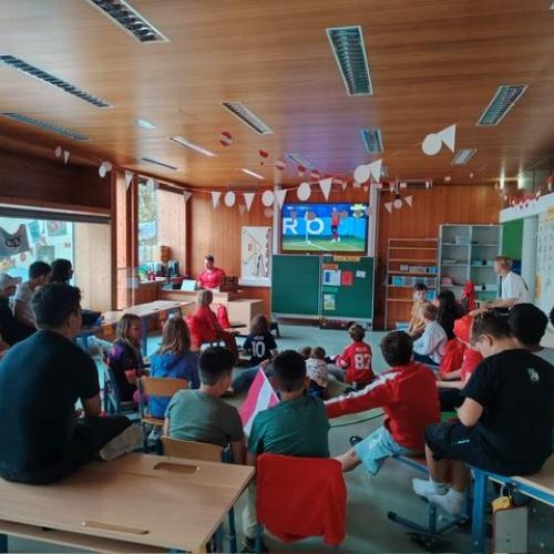 Blick von hinten auf den Bildschirm - alle Kinder sitzen verteilt im Raum