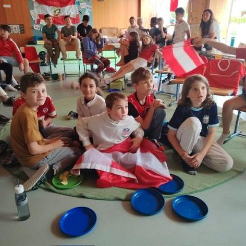 Die Kinder sitzen am Boden mit Fahnen und Österreich-Deko
