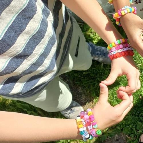 Man sieht nur die Finger der Kinder, die Herzen fomen und ihre Armbänder