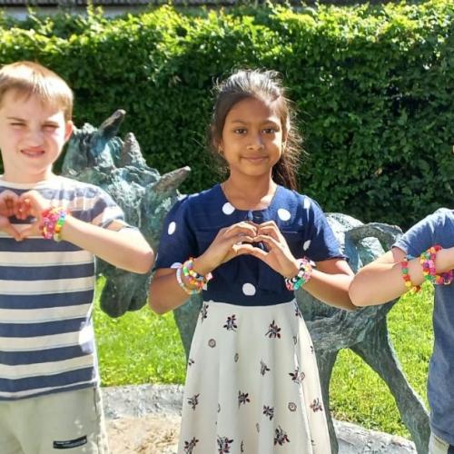 drei Kinder zeigen mit ihren Fingern Herzen in die Kamera