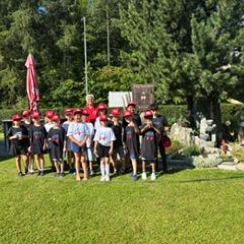 Die Kinder stehen als Gruppenbild auf einer grünen Wiese