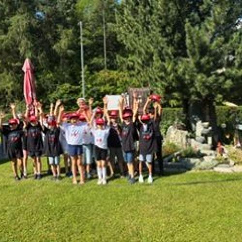 Mit erhobenen Armen stehen die Kinder in der Gruppe und lachen in die Kamera