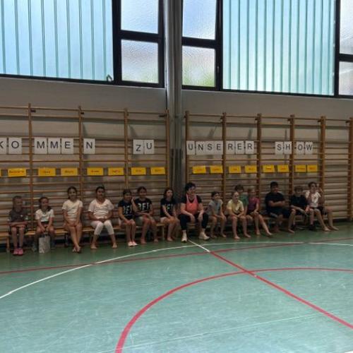 Alle Kinder sitzen mit Fr. Schwerma in der Mitte auf der Langbank