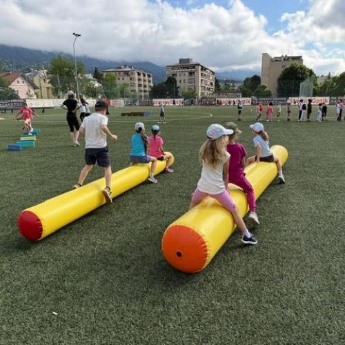 2 gelbe aufgeblasene Hüpfstangen lieben nebeneinander, Kinder sitzen und springen darauf