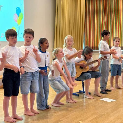 Kinder in Weiß und Jeans singen und bewegen sich zum Lied