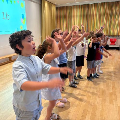 seitlicher Blick auf Kinder, die die Arme hochschwingen und singen