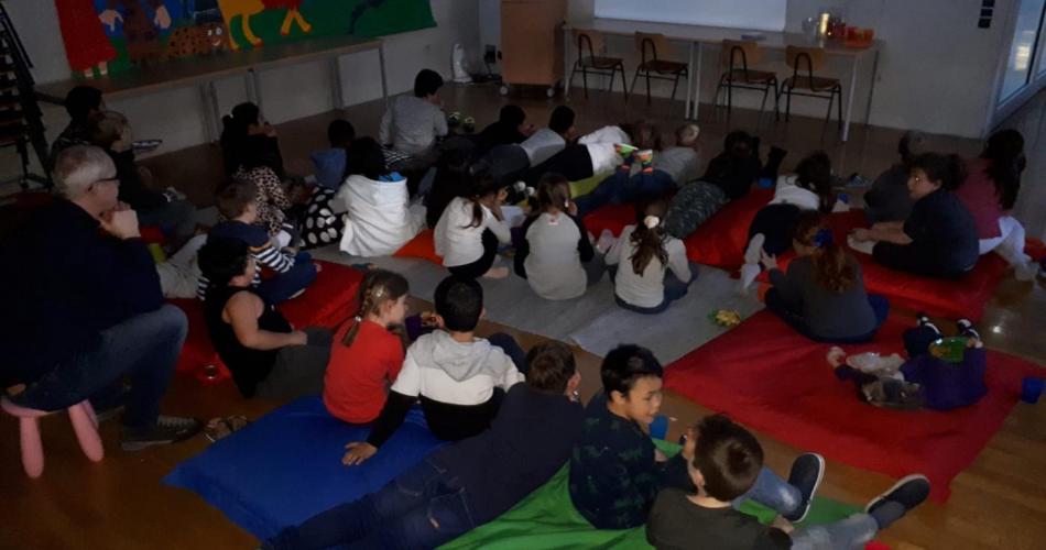 Kinder sitzen vor der Kinoleinwand im Medienraum